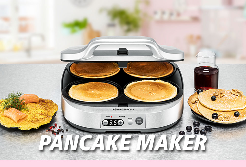 Ein silberner Pancake-Maker mit geöffnetem Deckel, in dem vier Pancakes liegen. Daneben Blaubeeren, Sirup, Räucherlachs und Kräuter. Im Bild steht in weißer Schrift: „PANCAKE MAKER“.