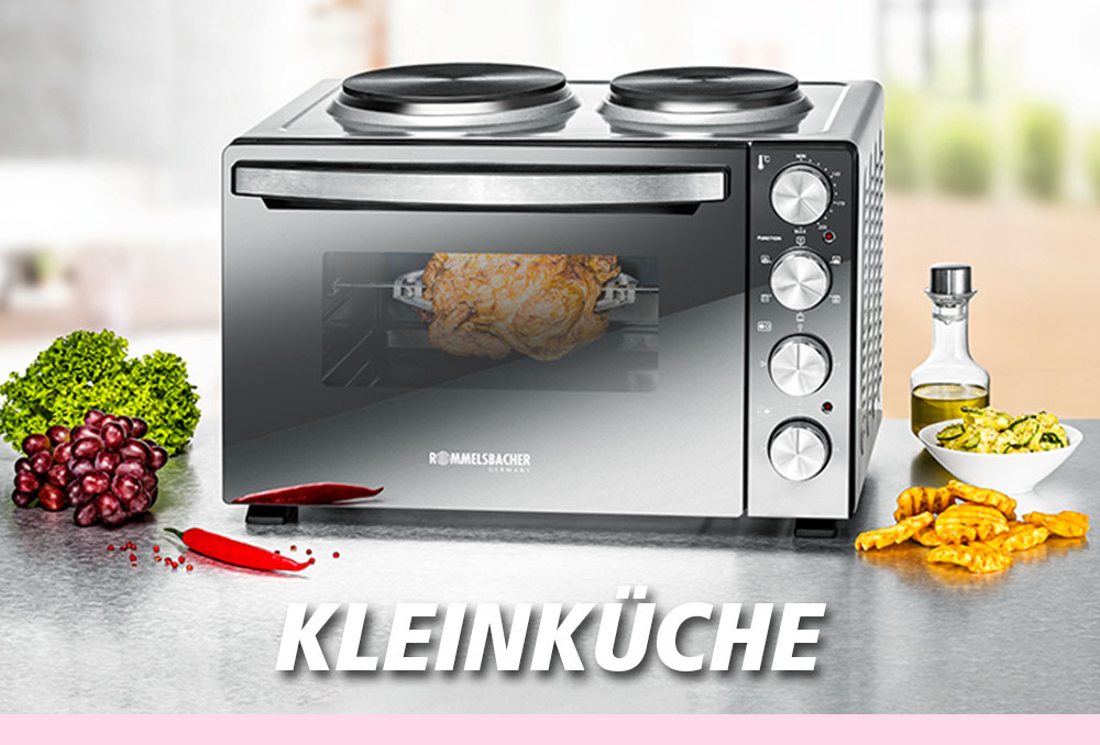 Eine silberne Miniküche mit zwei Kochplatten oben und einem kleinen Backofen darunter. Im Ofen befindet sich ein Braten. Daneben liegen Weintrauben, Brokkoli, Pommes und Öl. Im Bild steht in weißer Schrift: „KLEINKÜCHE“.